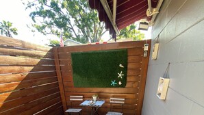 A wooden deck with a small seating area, a decorative wall with a green turf patch, and a potted plant. - Luxury, cozy, and Charming studio with WiFi and AC in brilliant Tampa (Tampa)