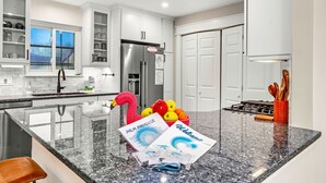 A modern kitchen with white cabinets, a stainless steel refrigerator, and a granite countertop.
