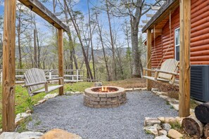 Relax by the fire pit in a serene forest setting, surrounded by a pergola and comfortable seating.