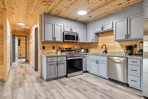 Enjoy cooking in this well-lit kitchen with a sleek finish, stainless steel appliances, and a spacious layout.