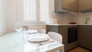 A clean, modern kitchen with white cabinets, a built-in oven, and a dining area with a table set for two. - Italianway - Frisi 8 B (Milan)