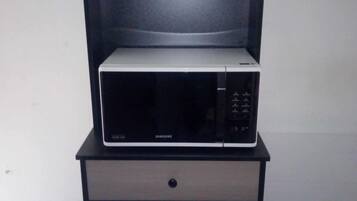Un four à micro-ondes posé sur un meuble, avec un tiroir en dessous.