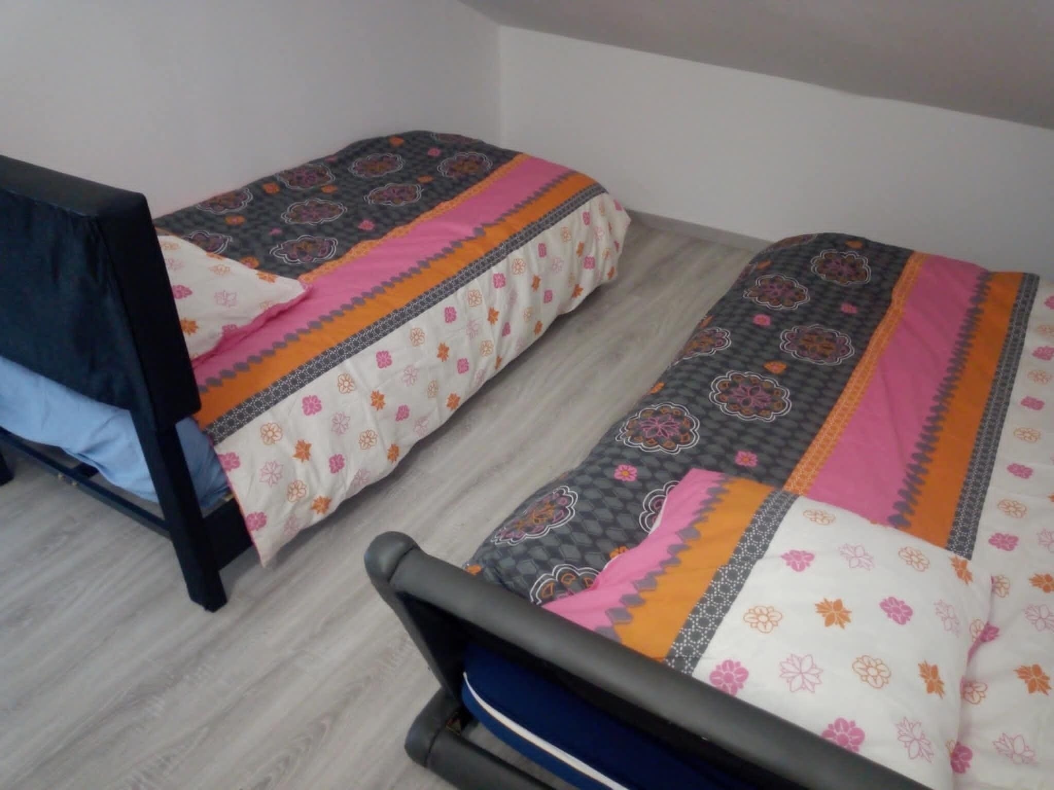 A small room with two single beds, each with patterned bedding.