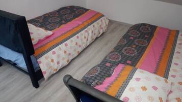 A small room with two single beds, each with patterned bedding.
