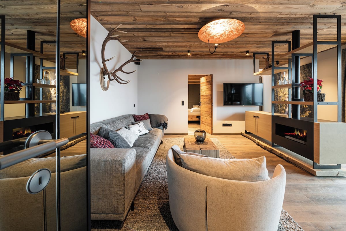 A modern living room with a sofa, armchair, and a fireplace.