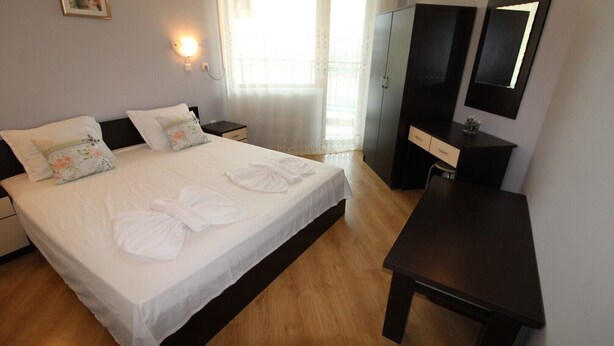 Habitación de hotel ordenada con cama, mesitas de noche, escritorio y armario.
