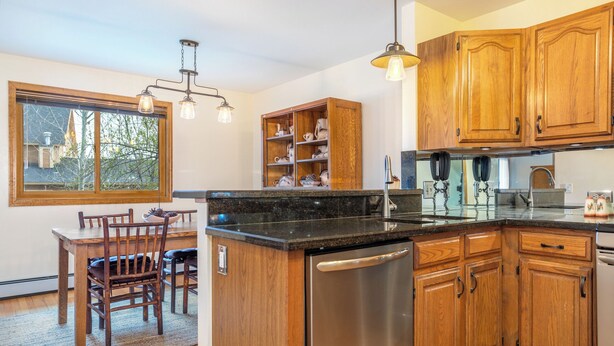 A kitchen with wooden cabinets, a stainless steel refrigerator, a built-in oven, and a window overlooking a tree. - 4 Bedroom Remodeled Home with Fenced in Backyard and Garage: Long Term Rental (Gypsum)