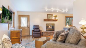 A cozy living room with a fireplace, leather armchair, and a sofa with patterned cushions. - 4 Bedroom Remodeled Home with Fenced in Backyard and Garage: Long Term Rental (Gypsum)