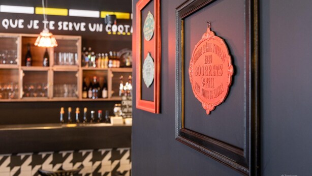 A bar area with shelves of bottles and glasses, a sign with text, and two framed items on the wall. - Apartment in Chantemerle With Family Ski Fun (Saint-Chaffrey)