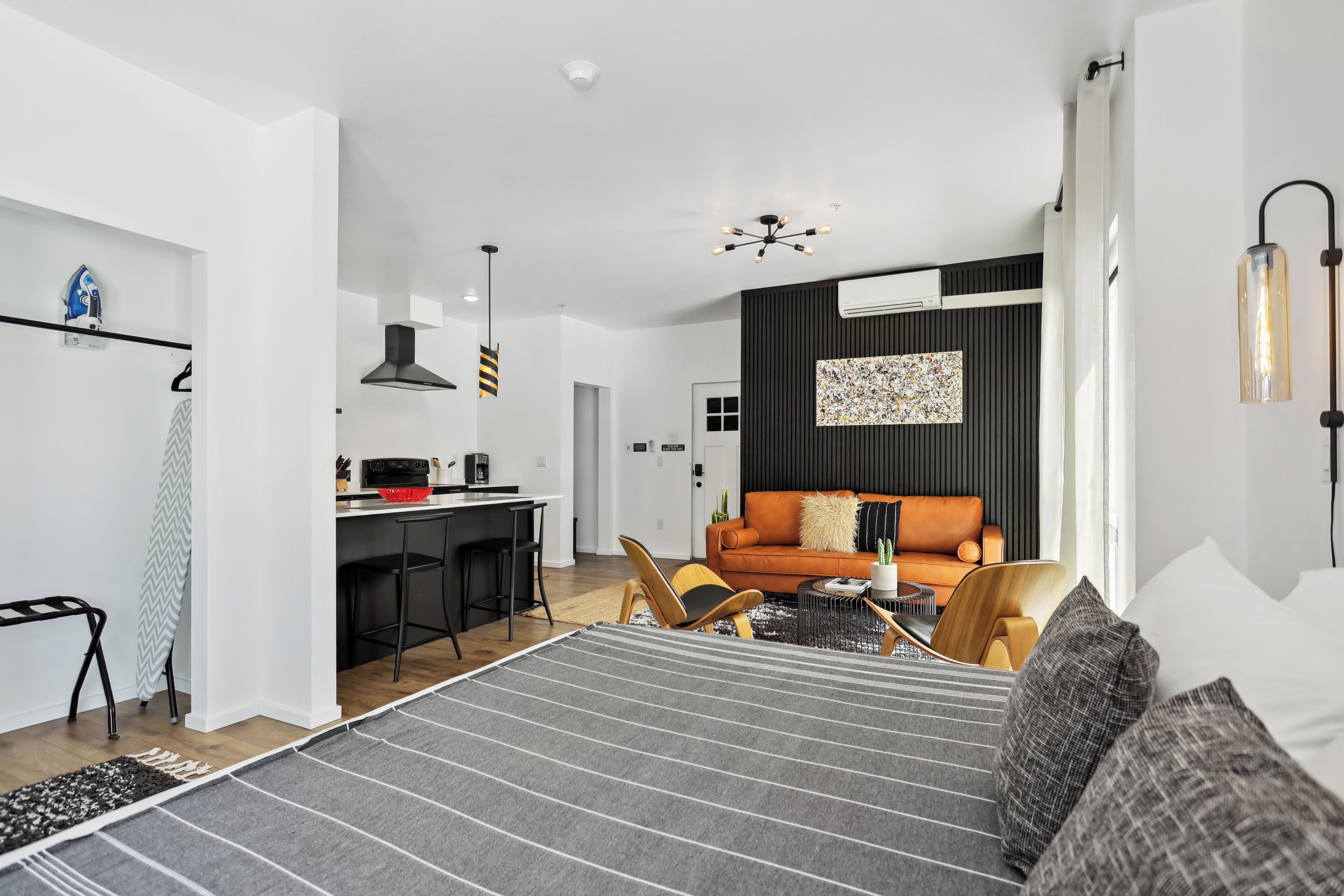 Ett modernt hotellrum med en stor säng, en matplats, en soffa och ett kök i bakgrunden.