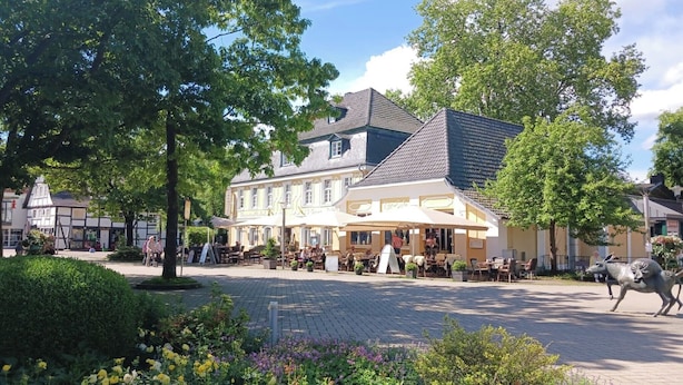 A public square with a café, outdoor seating, and a statue. - Parkhotel & Kurcafe Bad Sassendorf (Bad Sassendorf)