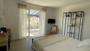 A bedroom with a bed, a TV, a wardrobe, and a chair. - Rsidence Patios di Pruno (Figari)