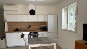 A compact kitchen with white cabinets, a wooden countertop, and a dining table with four chairs. - Rsidence Patios di Pruno (Figari)