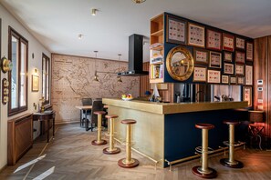 A bar area with a wooden bar counter, multiple stools, a map on the wall, and framed certificates.