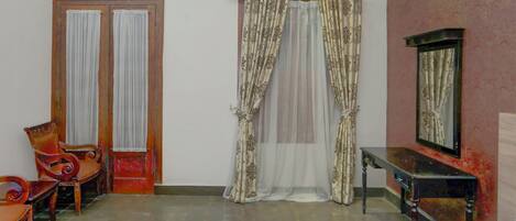 A room with a bed, two chairs, a table, and a mirror.