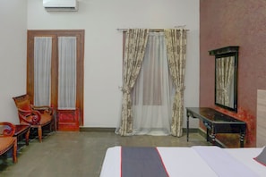 A room with a bed, two chairs, a table, and a mirror. - Hotel O Bogor near Kebun Raya Bogor formerly Guest House Saputra (Bogor)