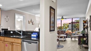 A kitchen with wooden cabinets, a black countertop, and a dishwasher. There is a dining area with a table and chairs.