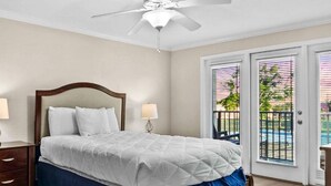 A bedroom with a bed, nightstands, a dresser, and a ceiling fan.