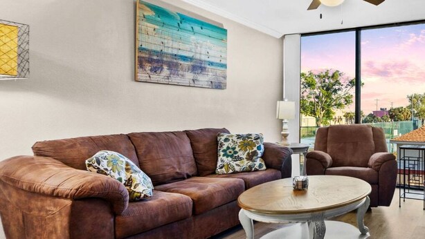 A living room with a brown leather sofa, a round wooden coffee table, and a brown armchair.