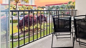 A balcony with a view of a landscaped garden and buildings in the background.