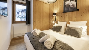 A bedroom with a bed, pillows, a blanket, a wall-mounted lamp, a window with curtains, and a framed picture on the wall. - Apartment in La Chapelle Near Cret-beni Lift (La Chapelle-d'Abondance)