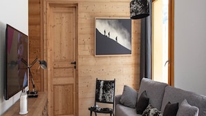 Un accogliente soggiorno con una porta in legno, un divano grigio, un quadro in bianco e nero appeso al muro e un tavolino rotondo.