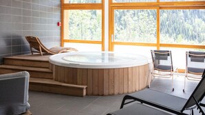 Un'area benessere con vasca idromassaggio, scalini in legno e posti a sedere.