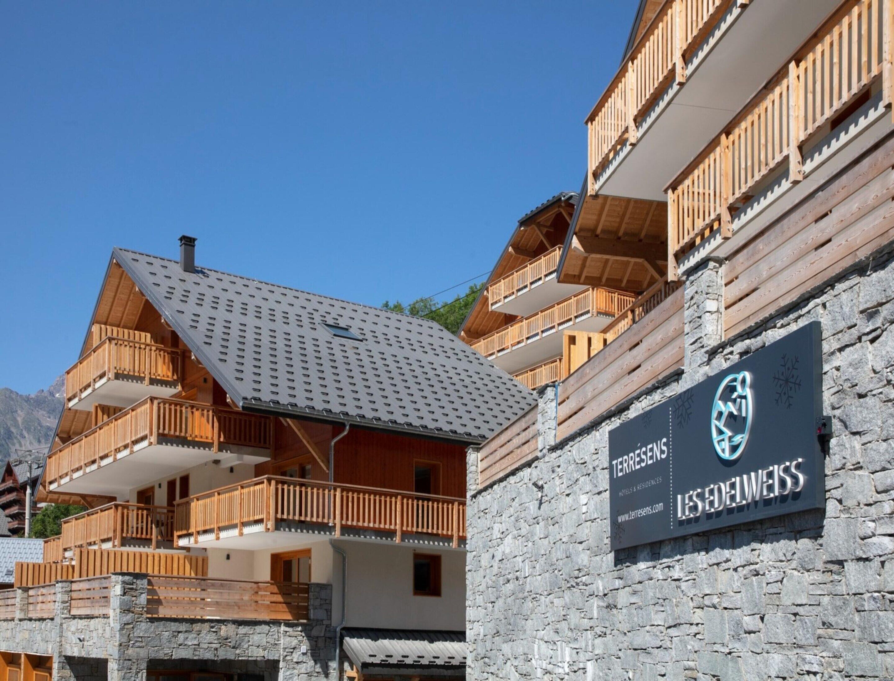 A hotel with a stone facade, wooden balconies, and a sign for 'Terres de Edelweiss'.