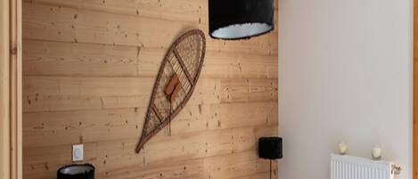 A bedroom with a wooden headboard, a bed with white bedding, two black lamps, and a radiator.