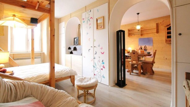 A cozy room with a bed, a small stool, and a dining area with a table and chairs. - 1st floor, balcony, tv, 40m², Serre Chevalier (Briançon)