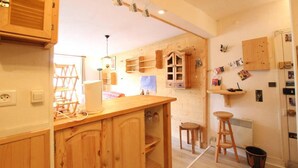 A compact kitchen with wooden cabinets, a central island, and a refrigerator. - 1st floor, balcony, tv, 40m², Serre Chevalier (Briançon)