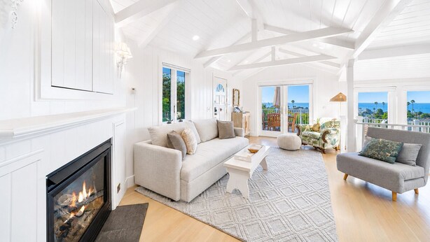 A spacious living room with a fireplace, a sofa, a coffee table, and a balcony with a view.
