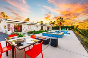 A modern outdoor patio with a dining table, red chairs, a fire pit, and a pool area. - 25% Off 30+ Stay! Prime Location Private Pool, Spa (Palm Springs)