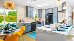 A modern kitchen with a central island, bright yellow chairs, and a view of greenery outside. - 25% Off 30+ Stay! Prime Location Private Pool, Spa (Palm Springs)