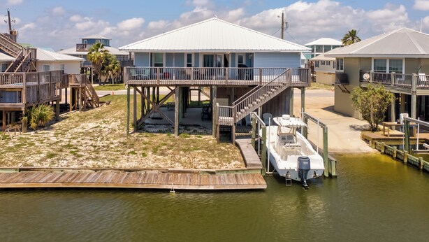 A waterfront house with a wooden deck, a boat dock, and a clear view of the water. - Canal-front, Boat Dock, Sleeps 9 - Anchor Eways (Dauphin Island)