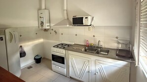Uma cozinha compacta com armários brancos, fogão a gás, micro-ondas e pia.