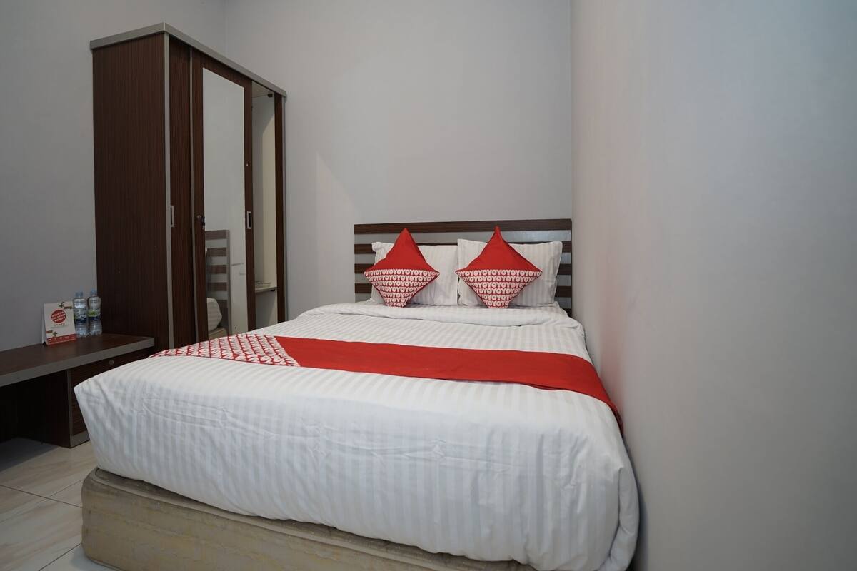 A bedroom with a bed, a wardrobe, and a bedside table.