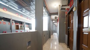 A corridor with grey walls, red-framed windows, and a tiled floor. - Hotel O Palembang Near Bumi Sriwijaya Stadium Formerly HPA Homestay (Palembang)