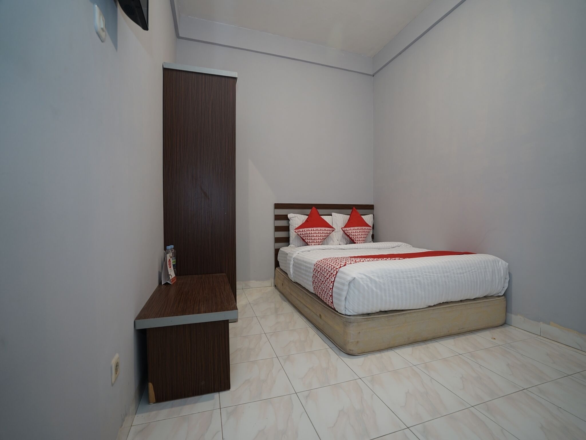 A bedroom with a bed, a wooden nightstand, and a wardrobe.