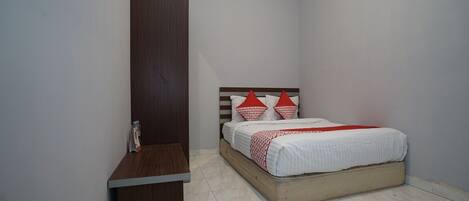 A bedroom with a bed, a wooden nightstand, and a wardrobe.