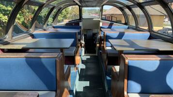 A vehicle interior with blue cushioned seating, a central aisle, and a view through the windows.