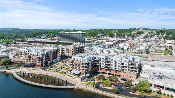 Un quartier urbain situé au bord de l’eau, avec des bâtiments modernes, un port de plaisance et une promenade piétonne.