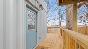 Une terrasse en bois avec une porte bleue et un paillasson.