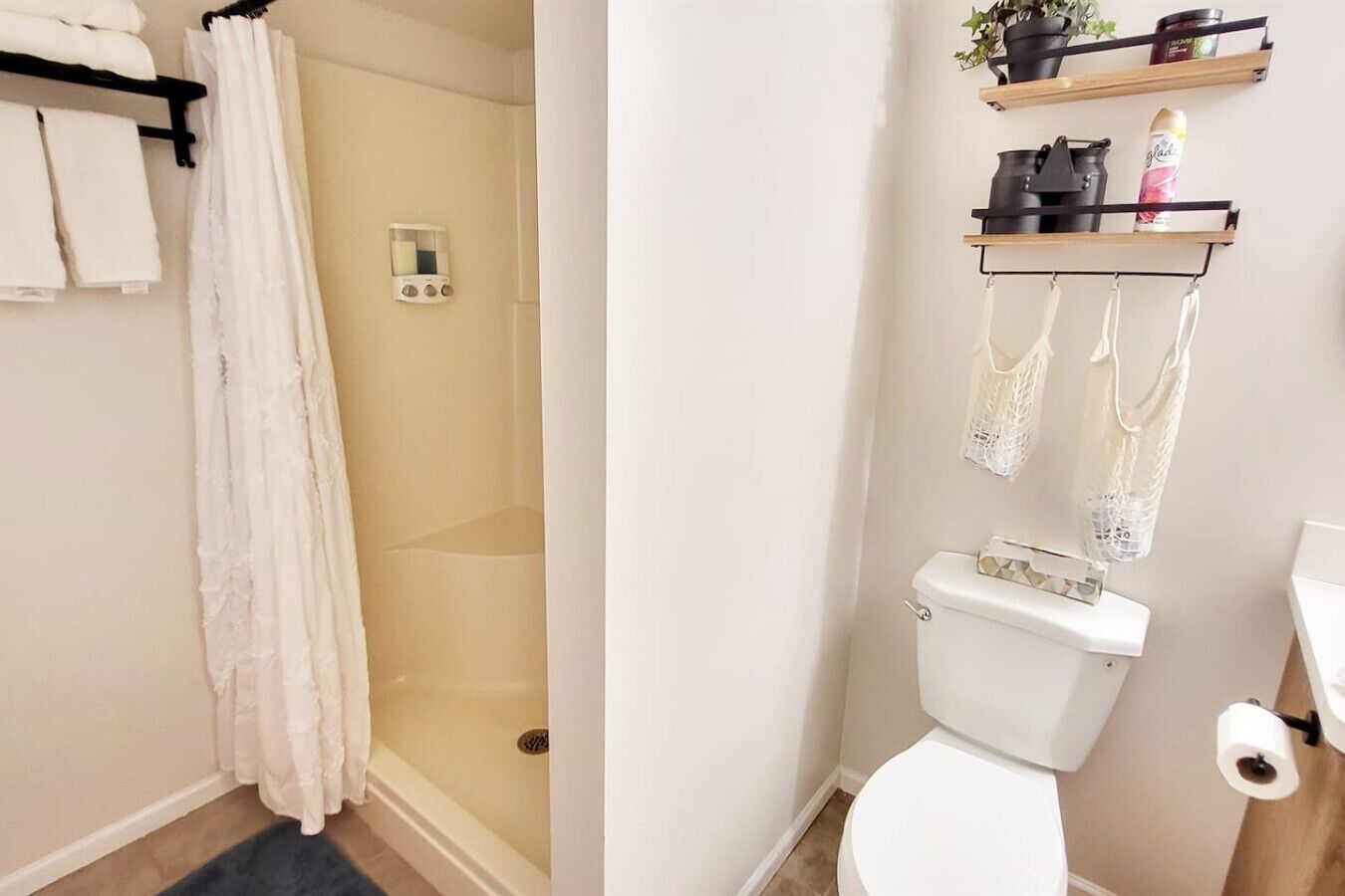 Une salle de bain équipée d’une douche, de toilettes et d’étagères où sont rangés les articles de toilette.