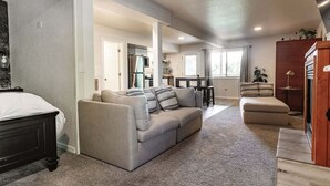 A spacious living area with a sofa set, a wooden cabinet, and a kitchen in the background. - Spa Studio Retreat w/ Lake Access + Sauna & Jacuzzi (Kimberling City)