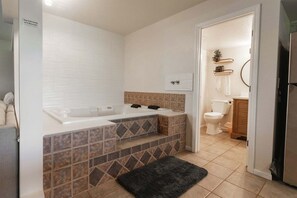 Bathroom features a white toilet, sink, and bathtub, with a shelf for personal items.