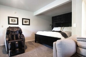 Relax in comfort with a large bed and a massage chair, perfect for unwinding in this well-appointed space.