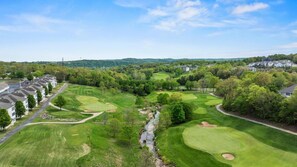 Un parcours de golf traversé par une rivière, entouré de bâtiments résidentiels.