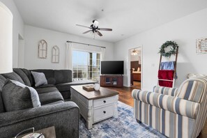 A living room with a sectional sofa, a striped armchair, a coffee table, and a television.