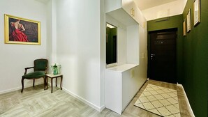 A hallway with a green wall, a white door, and a mirror. There is a chair and a small table with a vase of flowers. - Charming apartment with WiFi, AC in fabulous Bar (Bar)